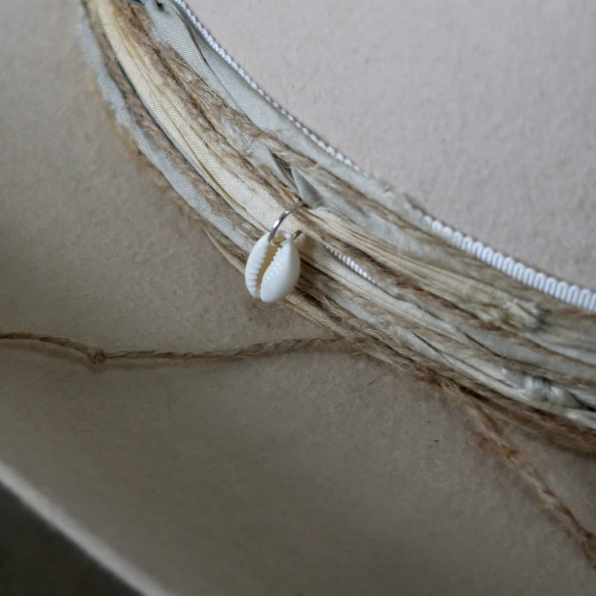 Close up detail of the Coastline Cowgirl felt cowboy hat showing cowrie shell charm and natural twine trim.