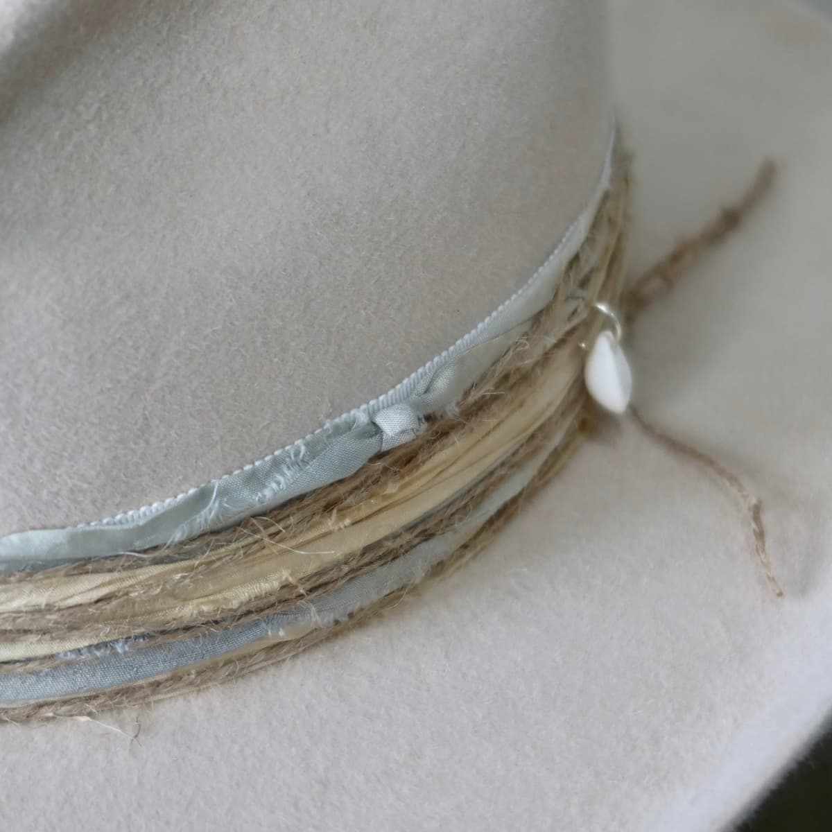 Close up detail of the Coastline Cowgirl felt cowboy hat showing sand and blue tie-dye sari silk trimming and twine wraps.
