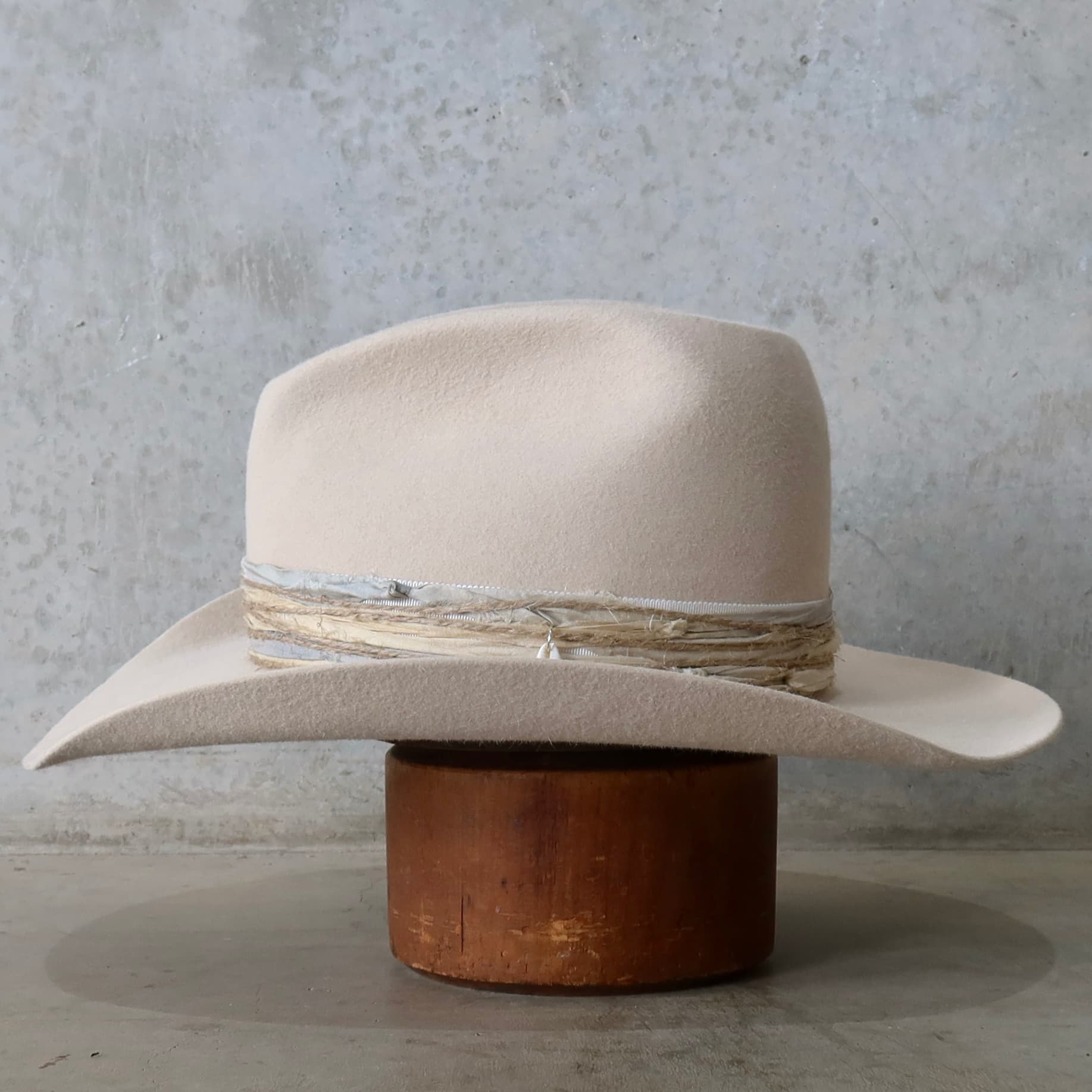 Left side view of the beige felt cowboy hat Coastline Cowgirl by PHYLLi Designs with layered twine wraps and sari silk trimming.