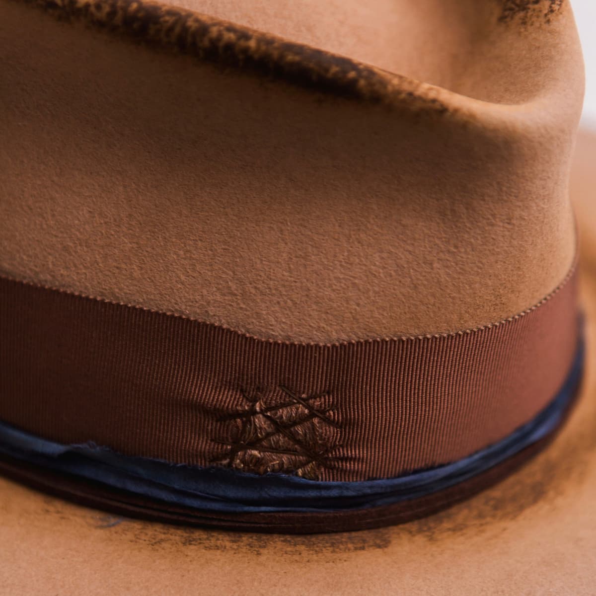 Close up detail of the Columbian felt hat showing the chocolate darned patch stitching on the grosgrain band.