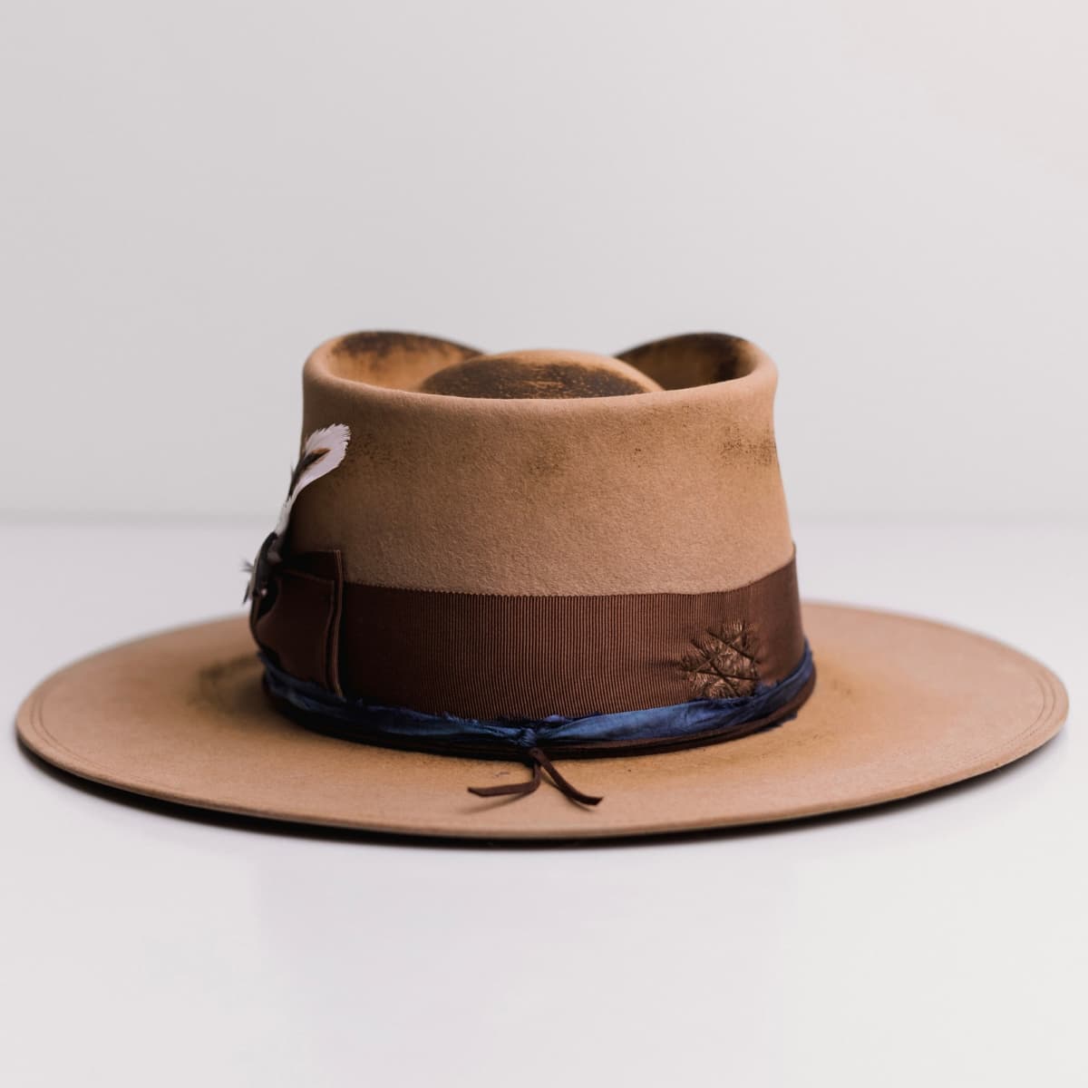 Back view of the Columbian camel felt hat by PHYLLi Designs featuring distressed chocolate darned patch stitching.