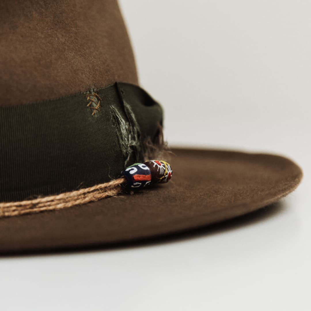 Close up detail of the Congo felt hat showing twine wraps with recycled glass beads and distressed grosgrain band.
