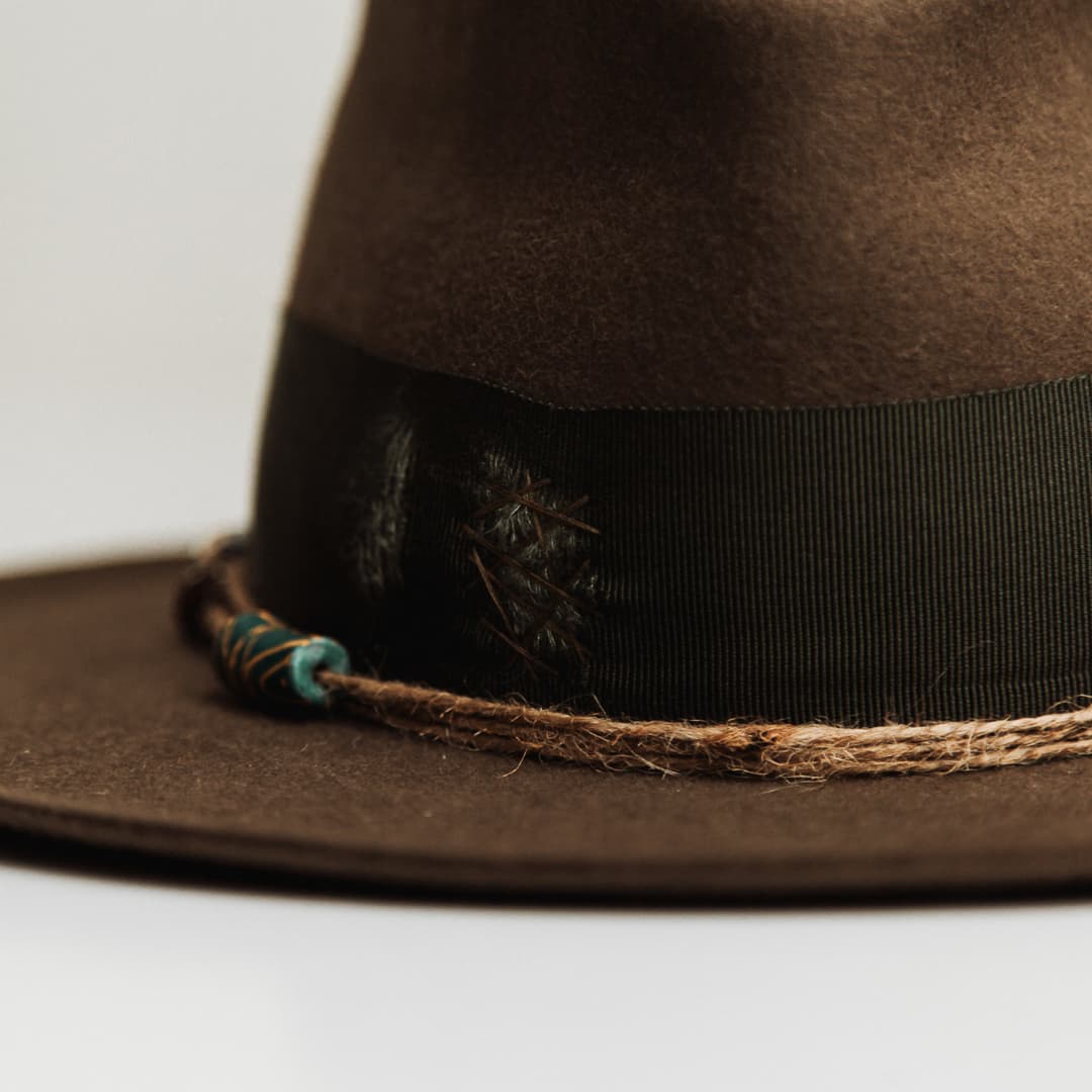 Close up detail of the Congo felt hat showing distressed moss darned patch stitched through the grosgrain band.
