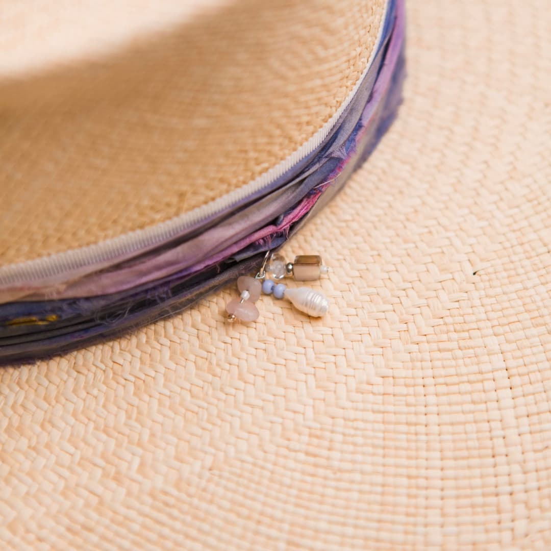 Close up detail of the Delfina Panama hat showing pearl, shell and rose quartz charm cluster.