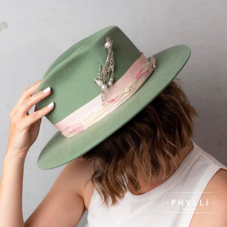 Woman wearing the Diamonds & Pearls eucalyptus felt hat by PHYLLi Designs with pearl beaded chunky silver hat pin and pink grosgrain band.