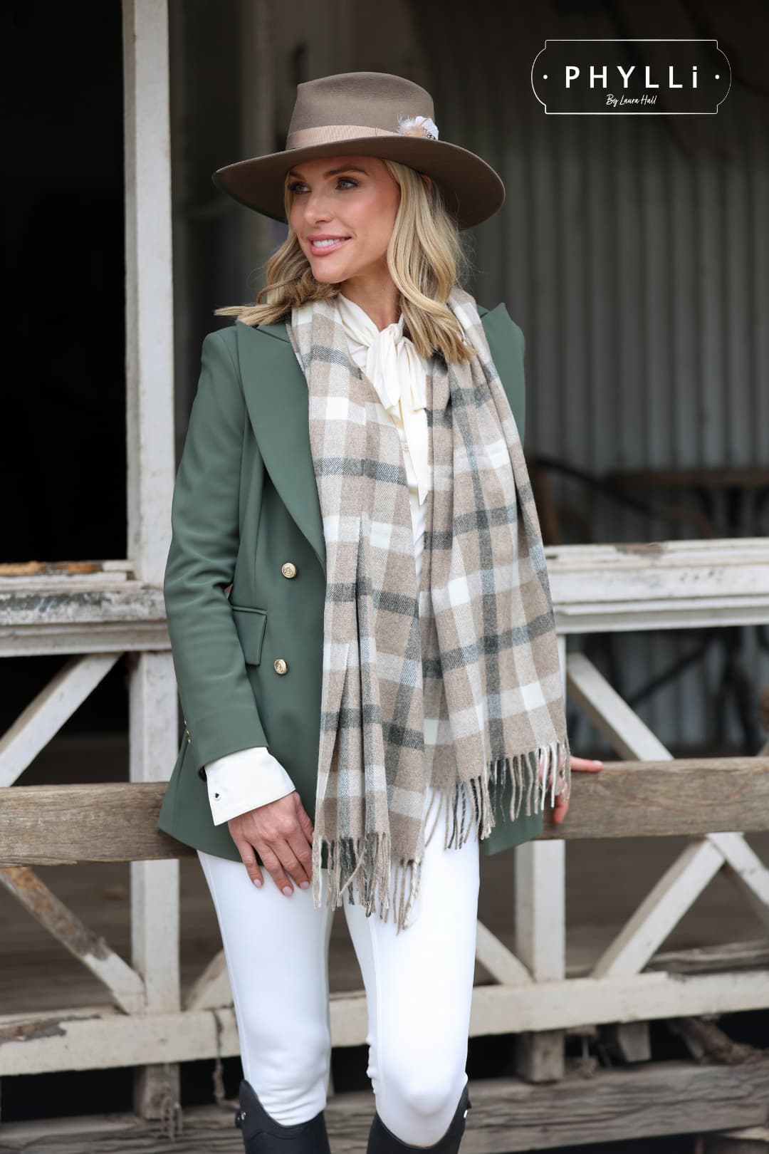Woman wearing the Dirty Jane dirty olive felt hat by PHYLLi Designs with taupe grosgrain ribbon band and feather detail in an equestrian outfit.
