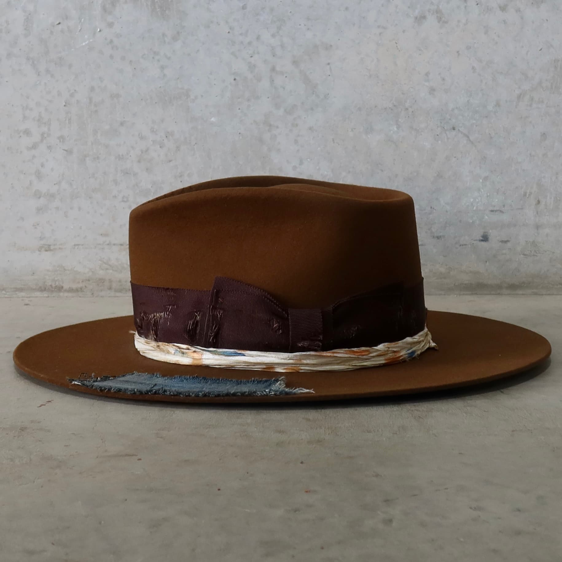 Left side view of the caramel felt hat Duke Limited Edition by PHYLLi Designs with distressed chocolate grosgrain double bow band.