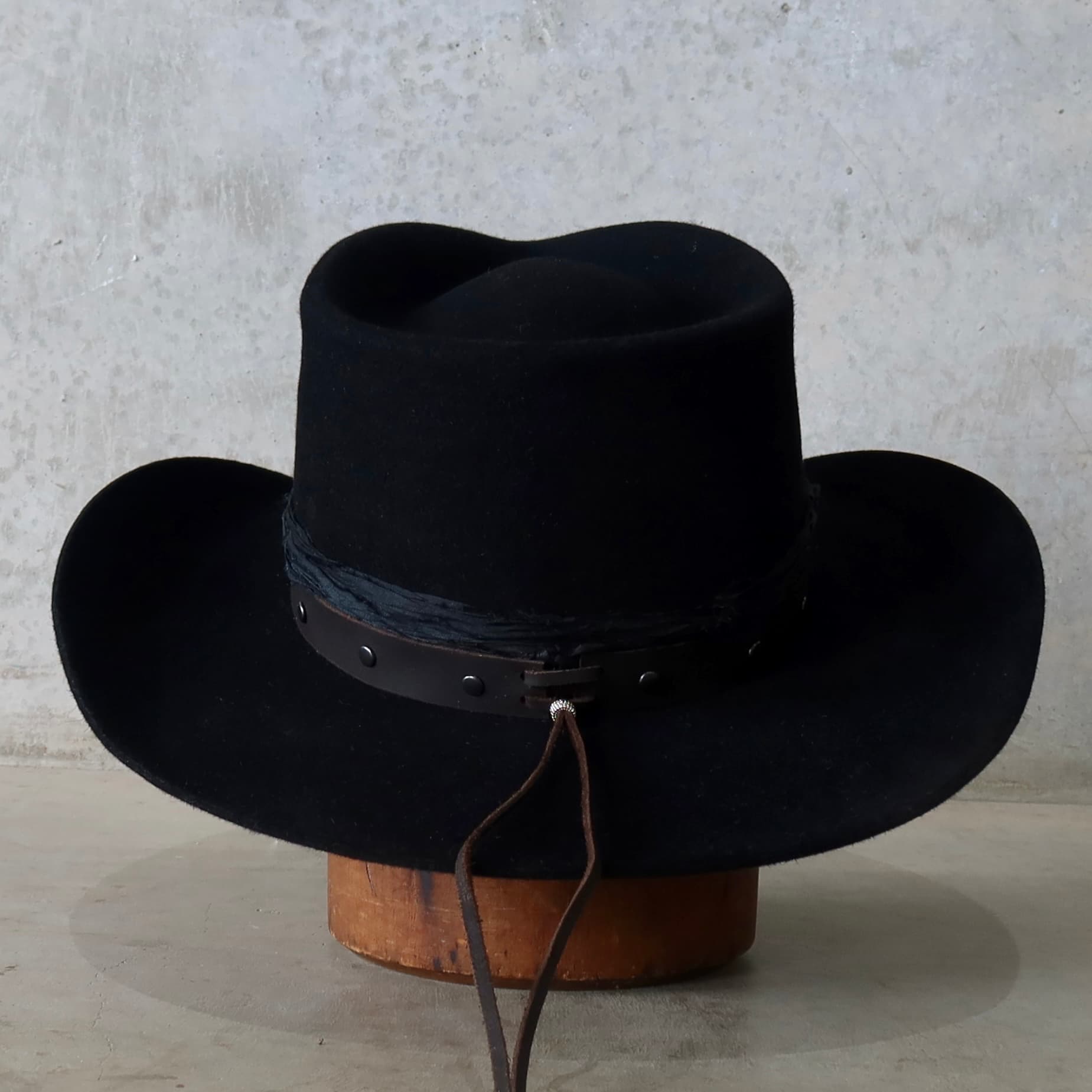 Back view of the black felt cowboy hat Edwards by PHYLLi Designs featuring buffalo leather tieback hat band.
