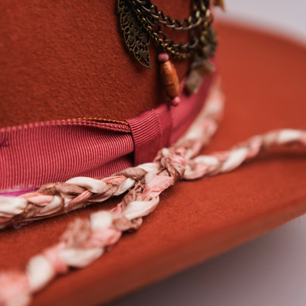 Close up detail of the Evans felt cowboy hat showing rust Japanese grosgrain band with watermelon bow and sari silk plaited trim.