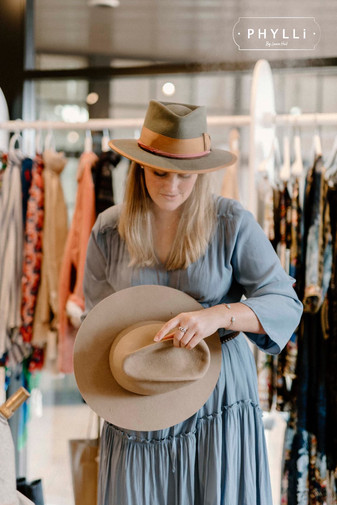 Laura Hall, founder of PHYLLi Designs, wearing the Feuille Morte felt hat while steaming a hat on location.
