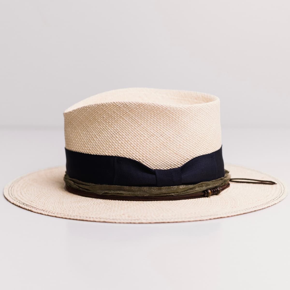 Left side view of the Natural Panama hat Figueras by PHYLLi Designs with chocolate suede string and wooden bead detailing.