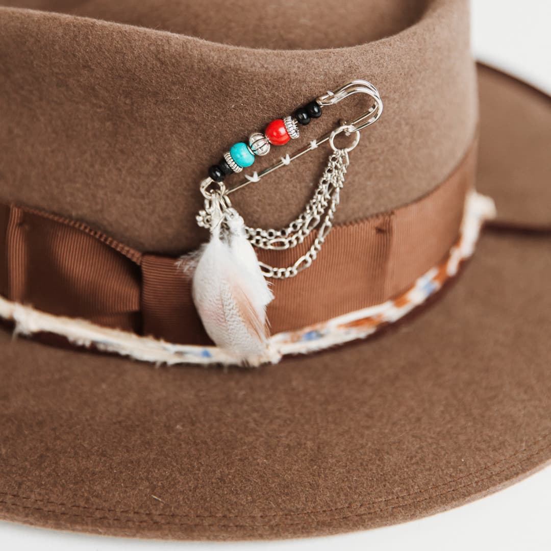 Close up of chunky hat pin with feathers, tassel, beading and chains on the Fly Fisher Havana hat by PHYLLi Designs.