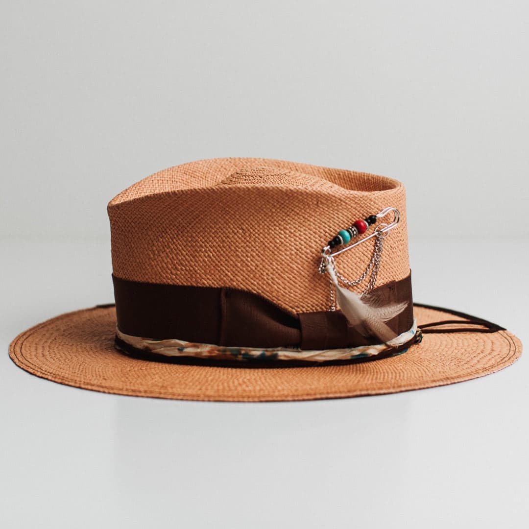 Left side view of the Fly Fisher Panama biscuit Panama hat by PHYLLi Designs featuring chunky silver hat pin with beading, feathers and chains.