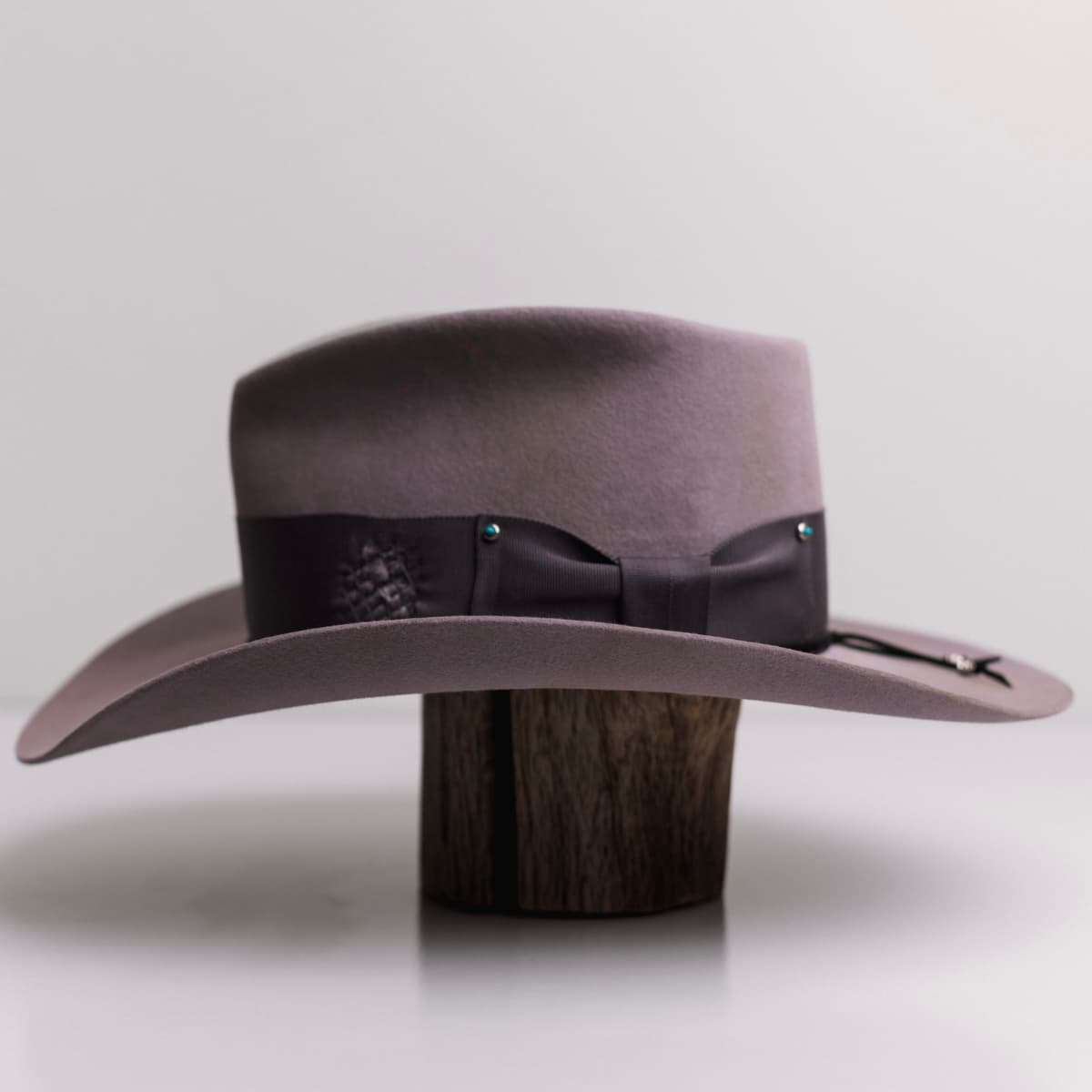 Left side view of the Franco Taupe distressed felt cowboy hat by PHYLLi Designs with black suede string and silver hardware.
