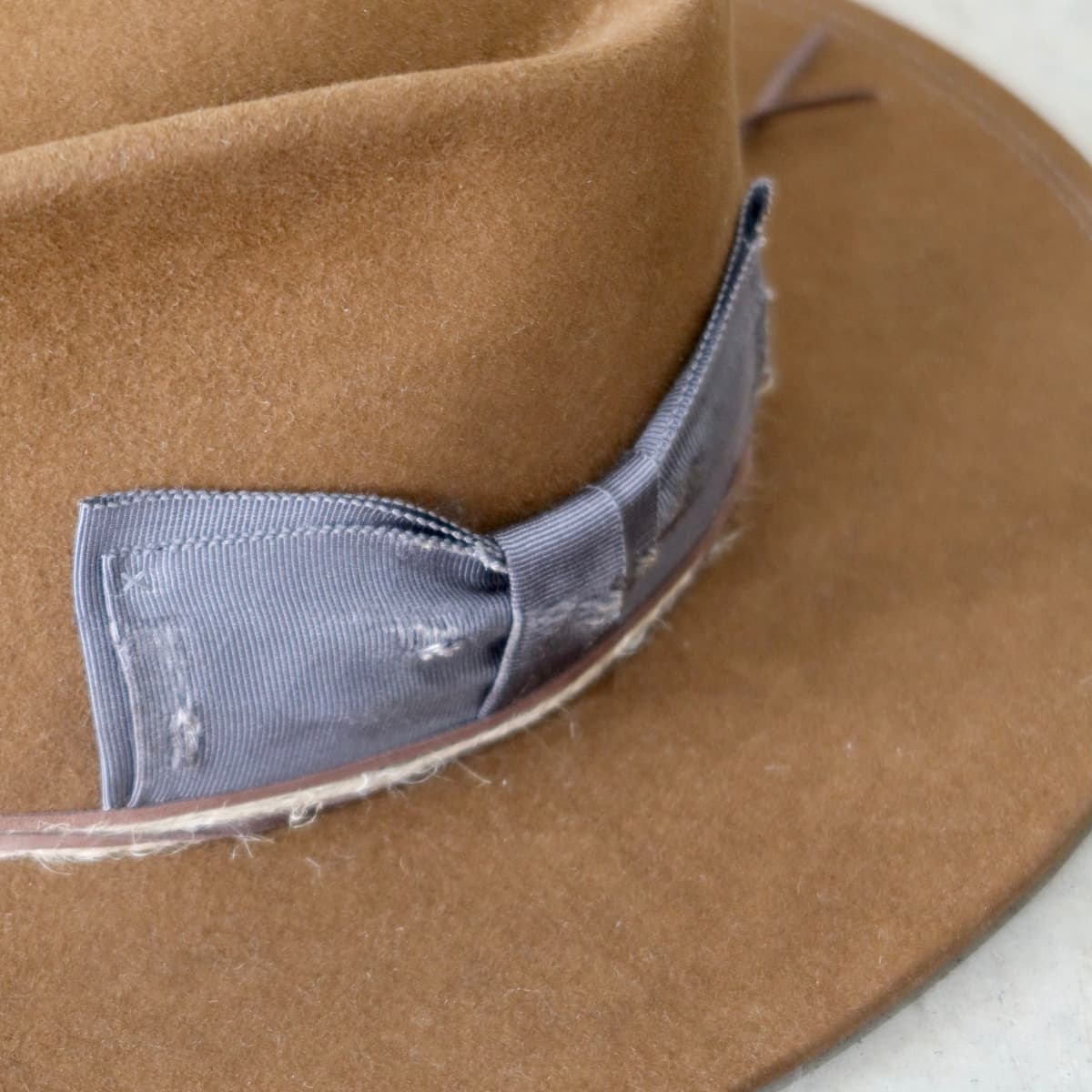 Close up detail of the George Limited Edition felt hat showing distressed steel Japanese grosgrain floating bow band.