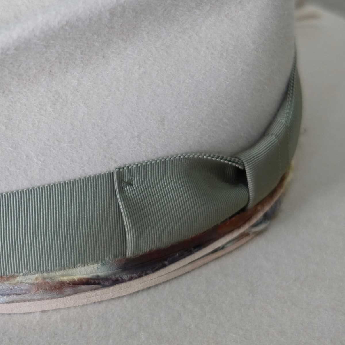 Close up detail of the Grasslands felt hat showing oil green Japanese grosgrain bow band and speckled blue sari silk trim.