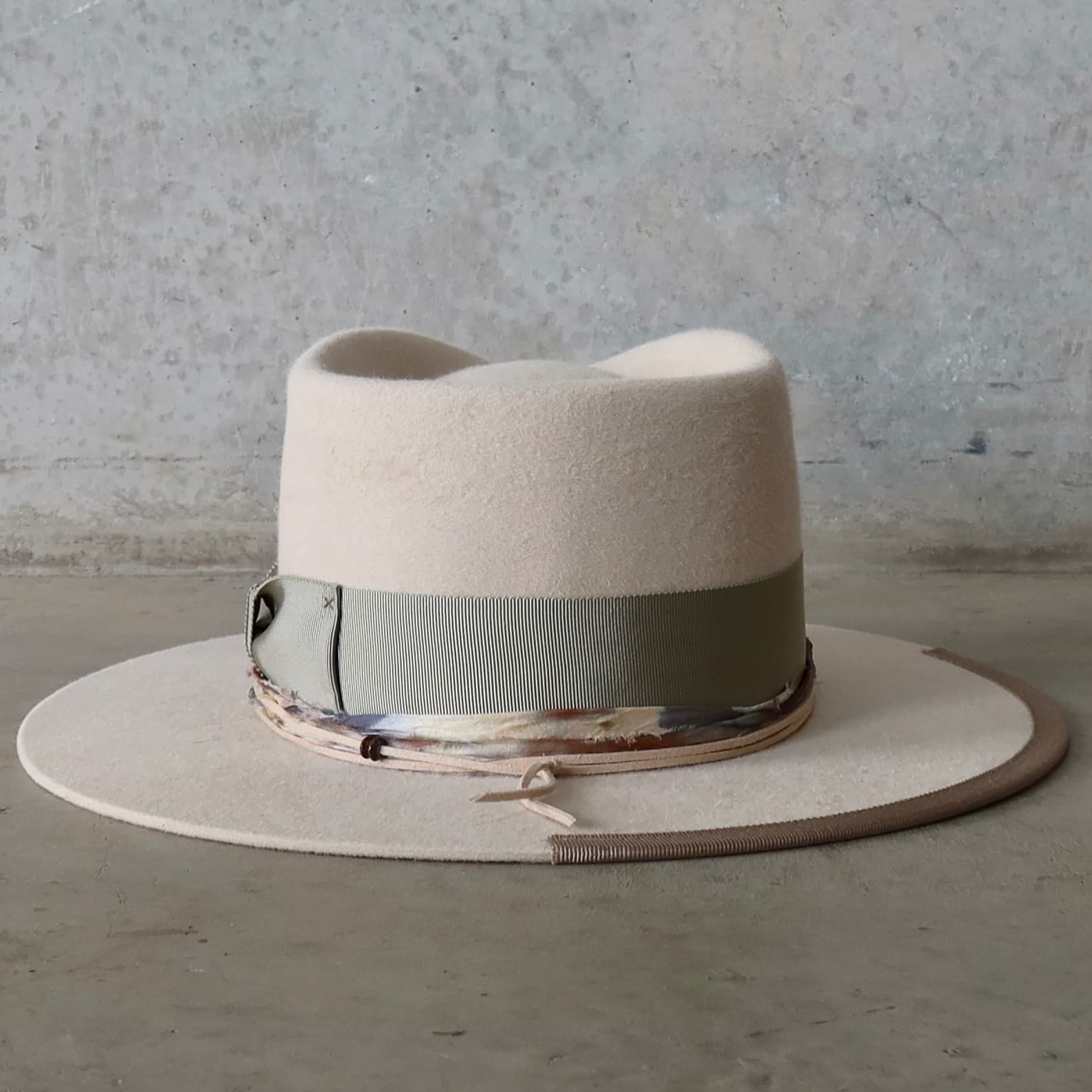 Back view of the beige felt hat Grasslands by PHYLLi Designs featuring nude suede string tie and wooden bead detail.