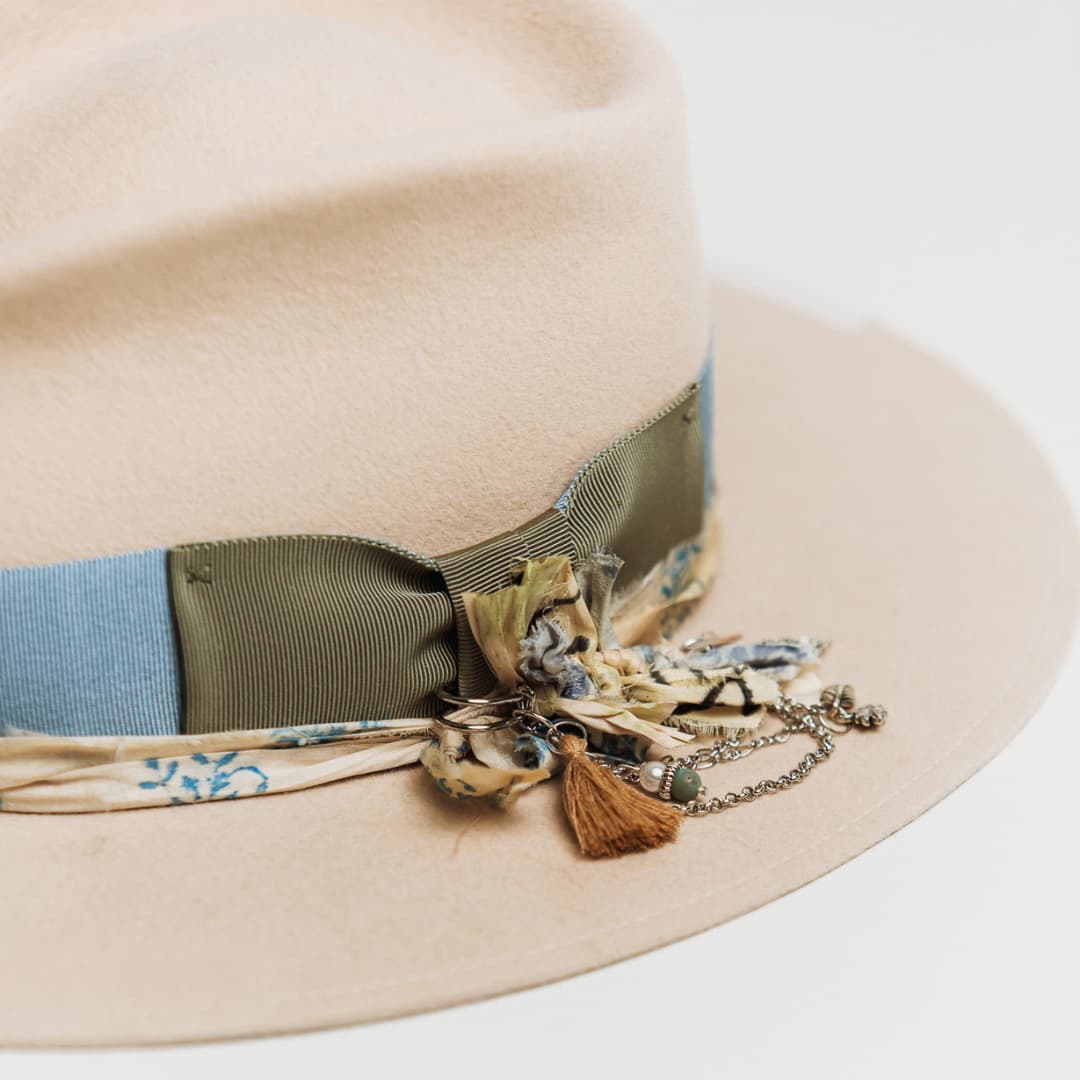 Close up detail of the Hunter felt hat showing silver chunky hat pin with ivory tassel, sari silks and charms.