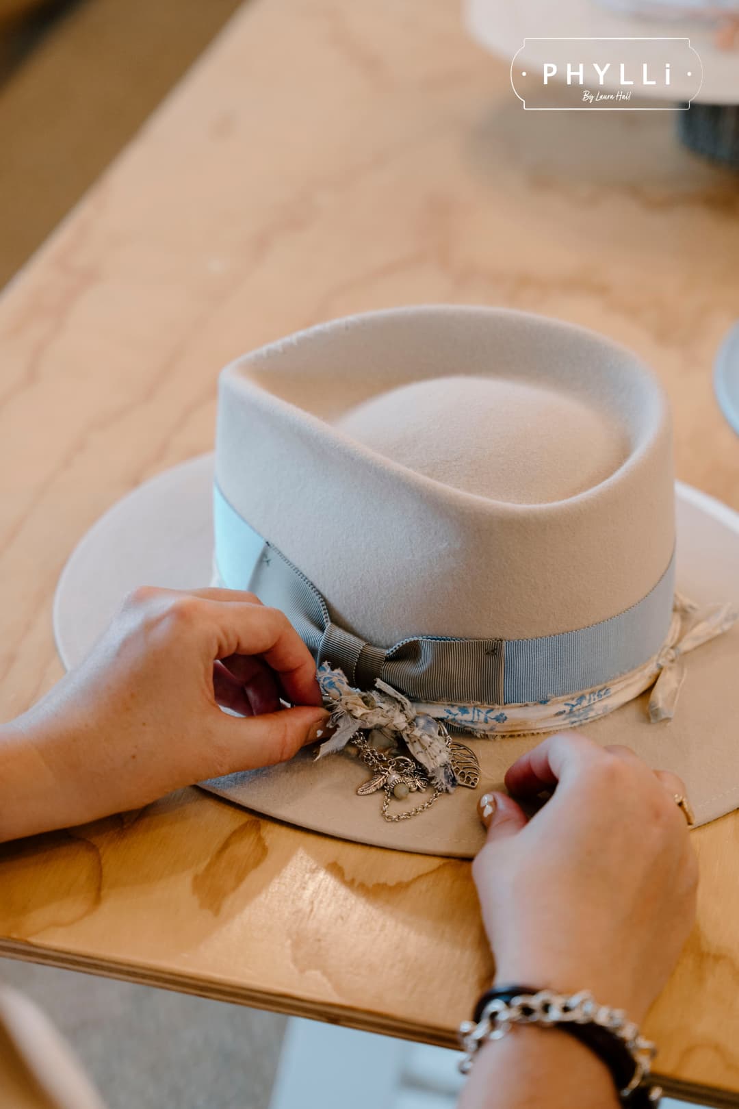 Woman styling the Hunter beige felt hat by PHYLLi Designs with a chunky hat pin.