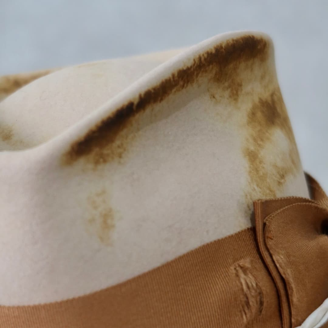 Close up detail of the Iluka cowboy hat showing the distressed sand felt finish and shaped crown edge.