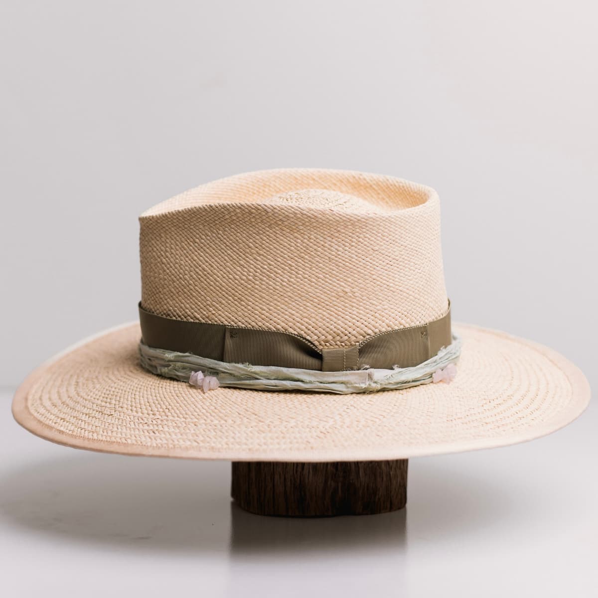 Left side view of the Isle of Skye 2.0 Natural Panama hat by PHYLLi Designs with oil green Japanese grosgrain bow band, mint sari silk trim and rose quartz crystal clusters.