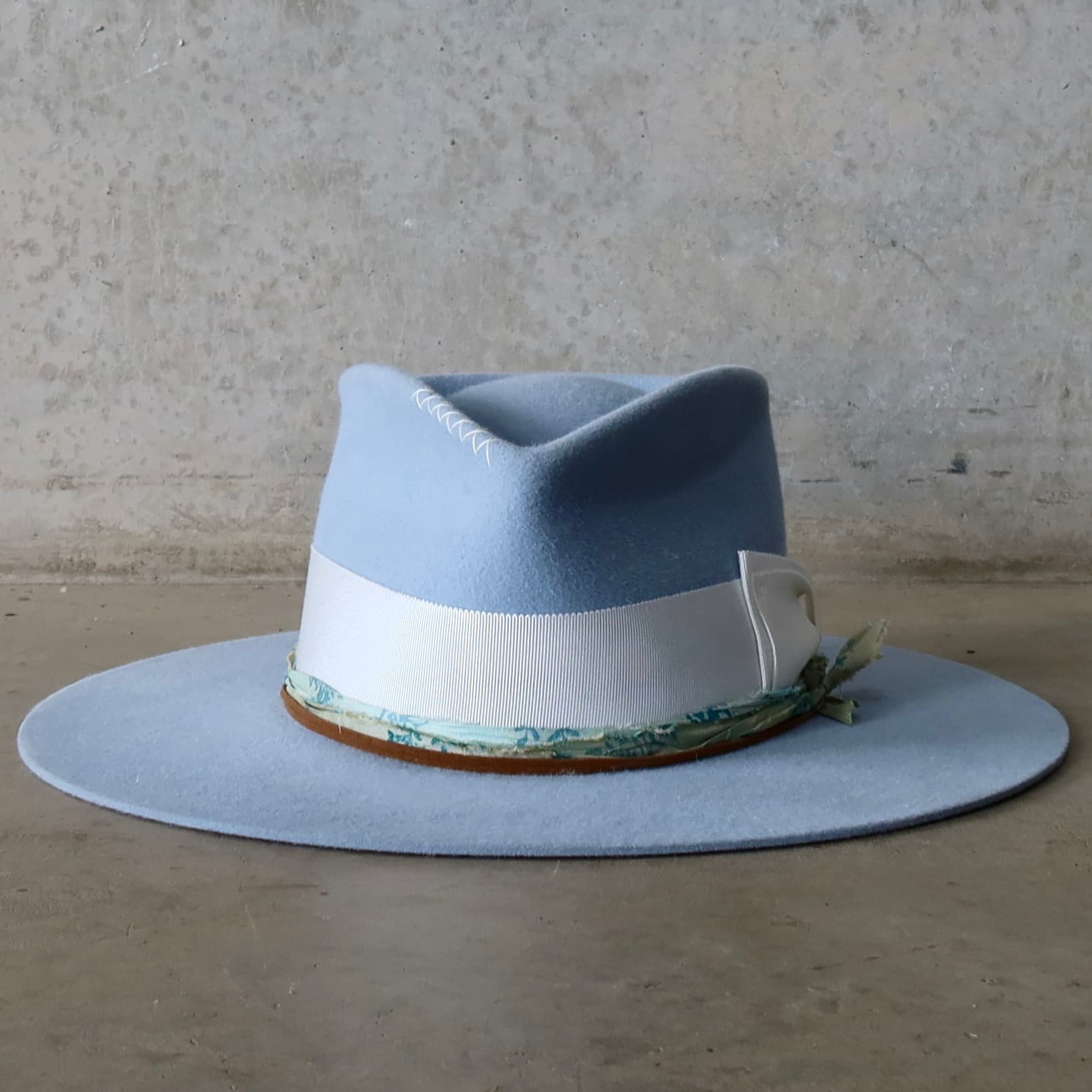 Crystal blue felt hat Jarvis by PHYLLi Designs with ivory Japanese grosgrain double bow band and blue-teal patterned sari silk trimming.