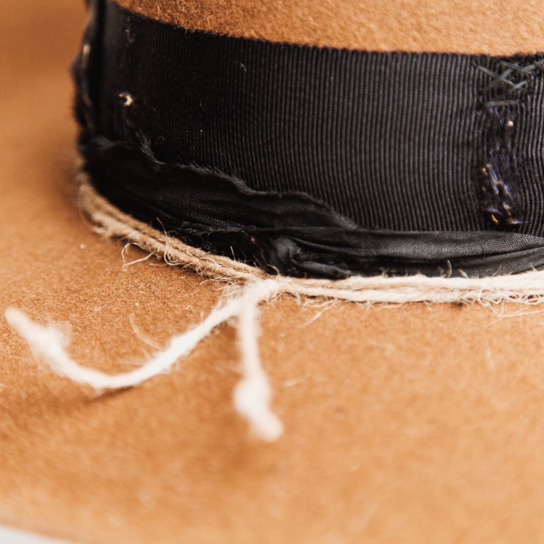 Close up detail of the Jersey felt hat showing distressed black grosgrain ribbon band with black darned patch stitching.