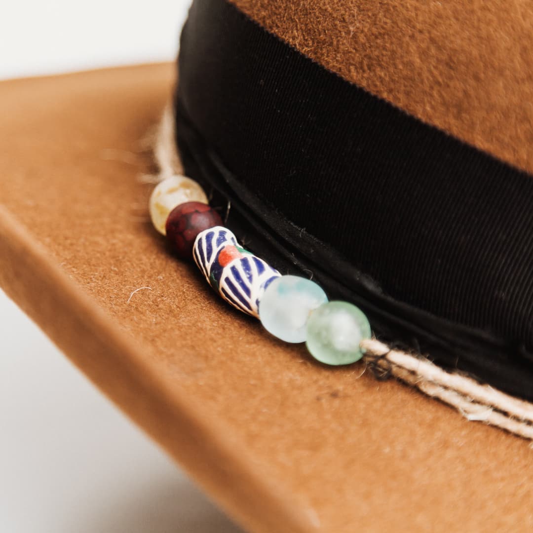 Close up detail of the Jersey felt hat showing hand painted recycled glass beads from Ghana on twine wrap.