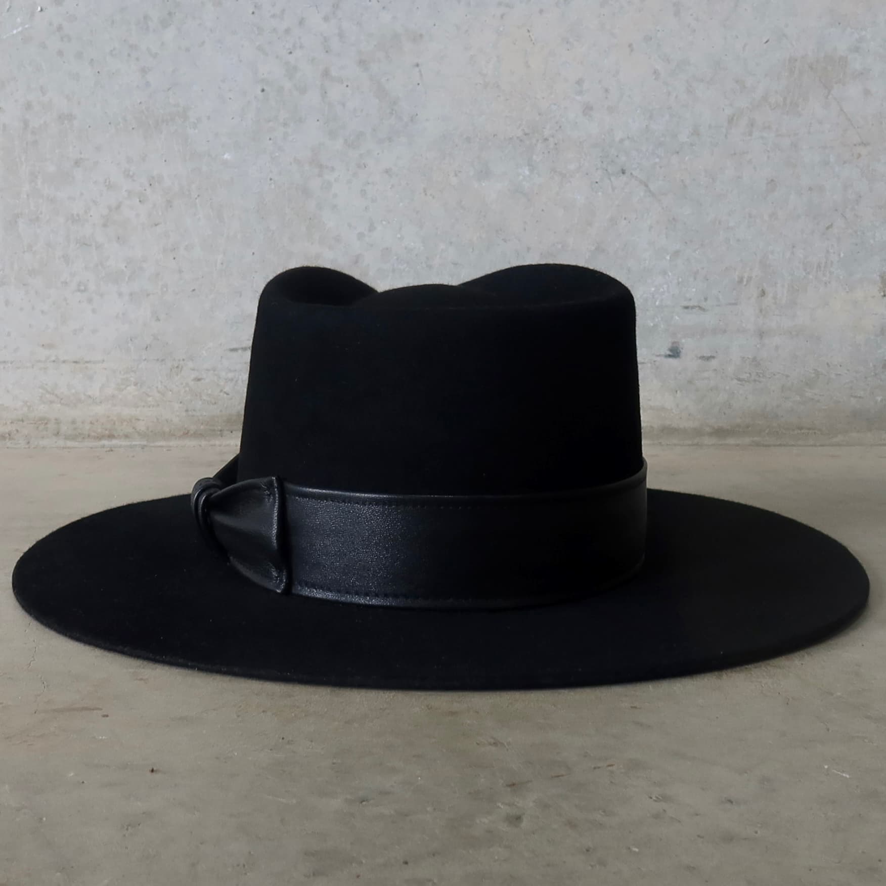 Back view of the black felt hat Kirrilee by PHYLLi Designs featuring sheepskin leather bow band.