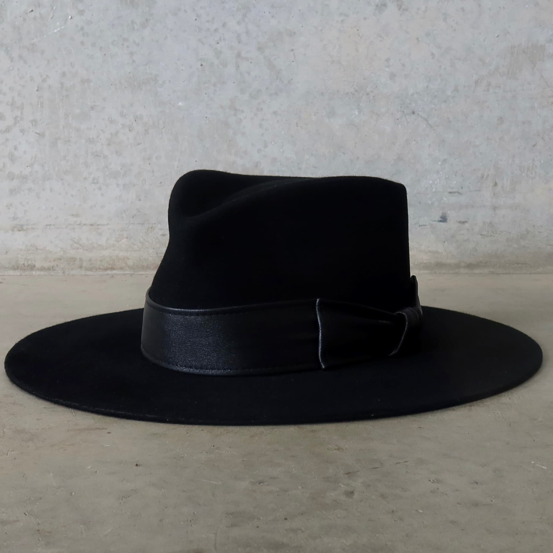 Front left angle of the black felt hat Kirrilee by PHYLLi Designs with sheepskin leather bow band.