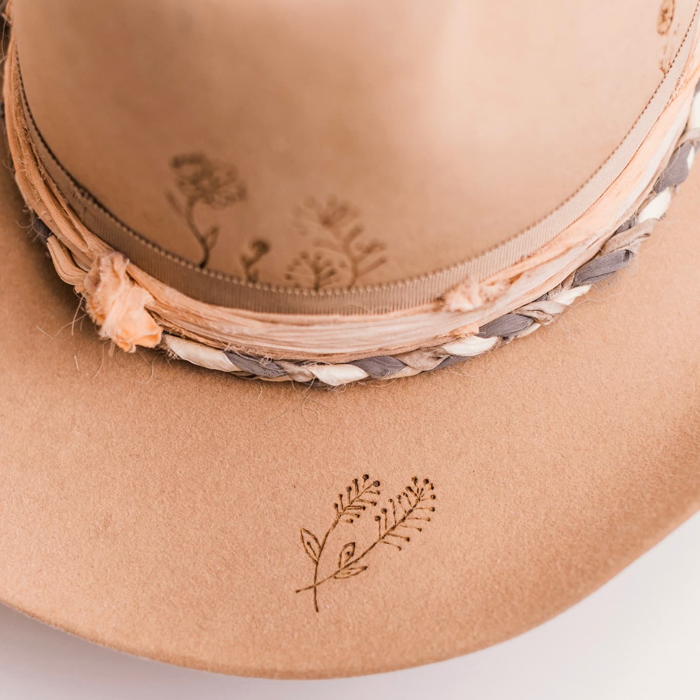 Close up detail of the La Fleurs camel felt cowboy hat by PHYLLi Designs showing plaited sari silk trim with soft peach sari silk wrap.