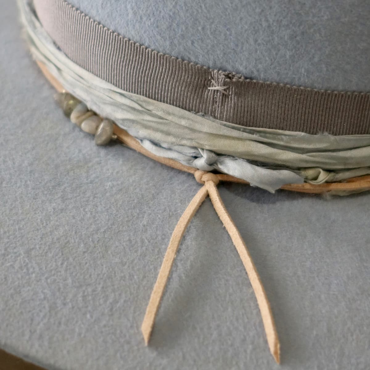 Close up detail of the La Journee felt hat showing nude suede string detail against the crystal blue felt.