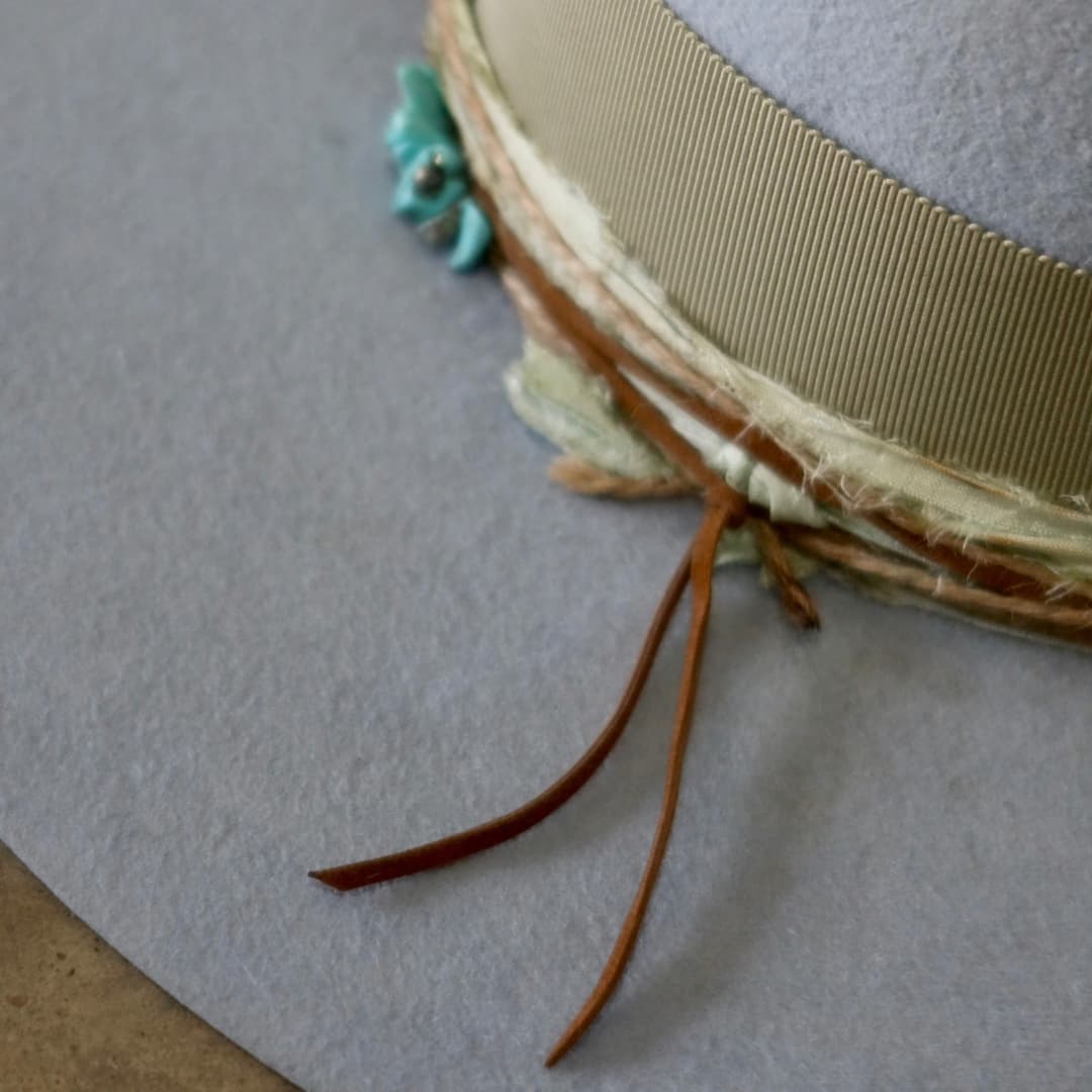Close up detail of the Lagoon felt hat showing tan suede string ties layered with twine wraps.