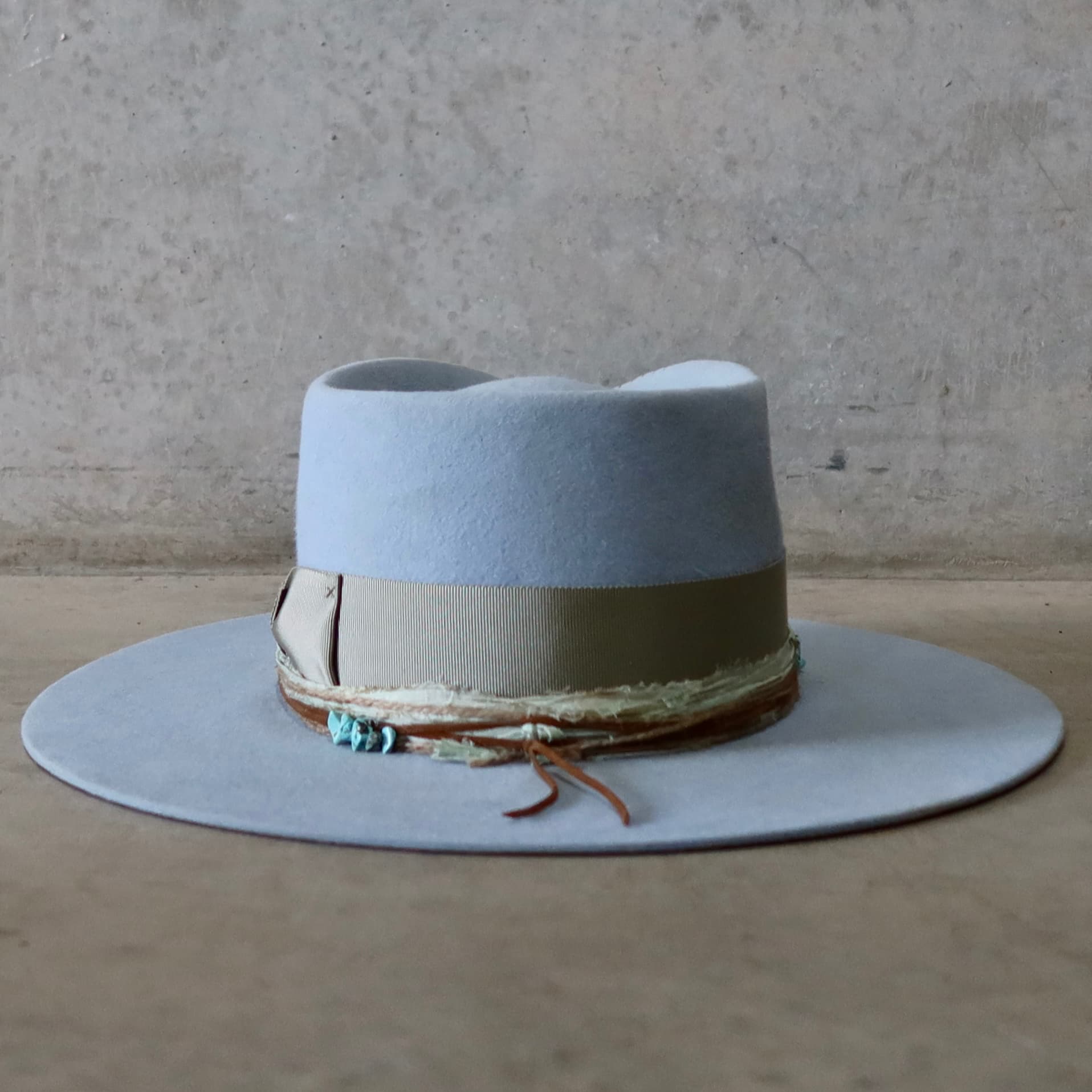 Back view of the crystal blue felt hat Lagoon by PHYLLi Designs featuring three twine wraps and tan suede string.