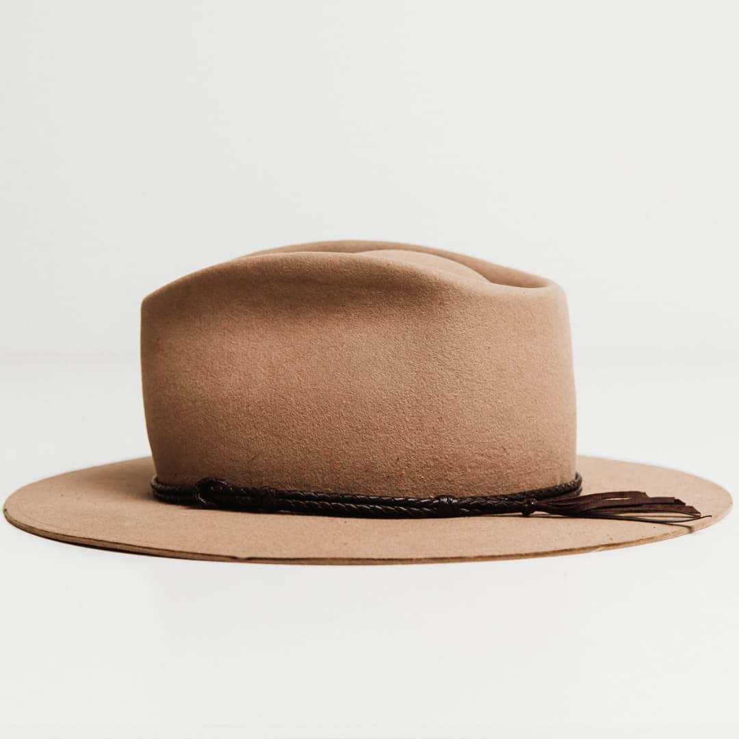 Left side view of the Laurie Hat Band featuring hand plaited dark brown kangaroo hide with tassel finish on a Sahara felt hat by PHYLLi Designs.