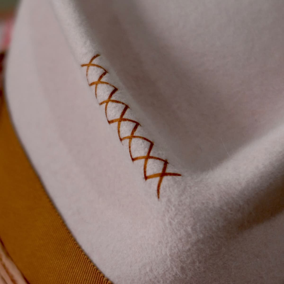 Close up detail of the Lexie felt hat showing hand stitched crosses in copper thread.