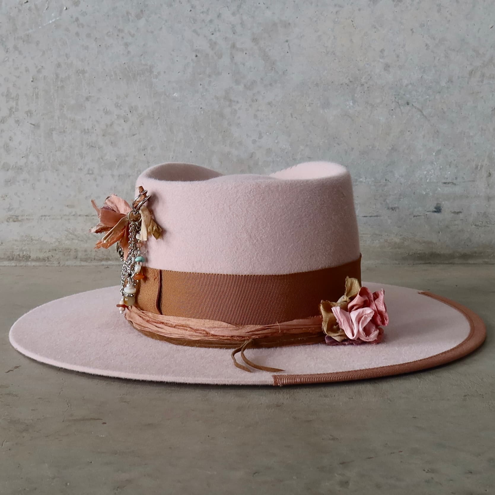 Back view of the baby pink felt hat Lexie by PHYLLi Designs featuring silver chunky hat pin with charms and sari silk lapel bloom.
