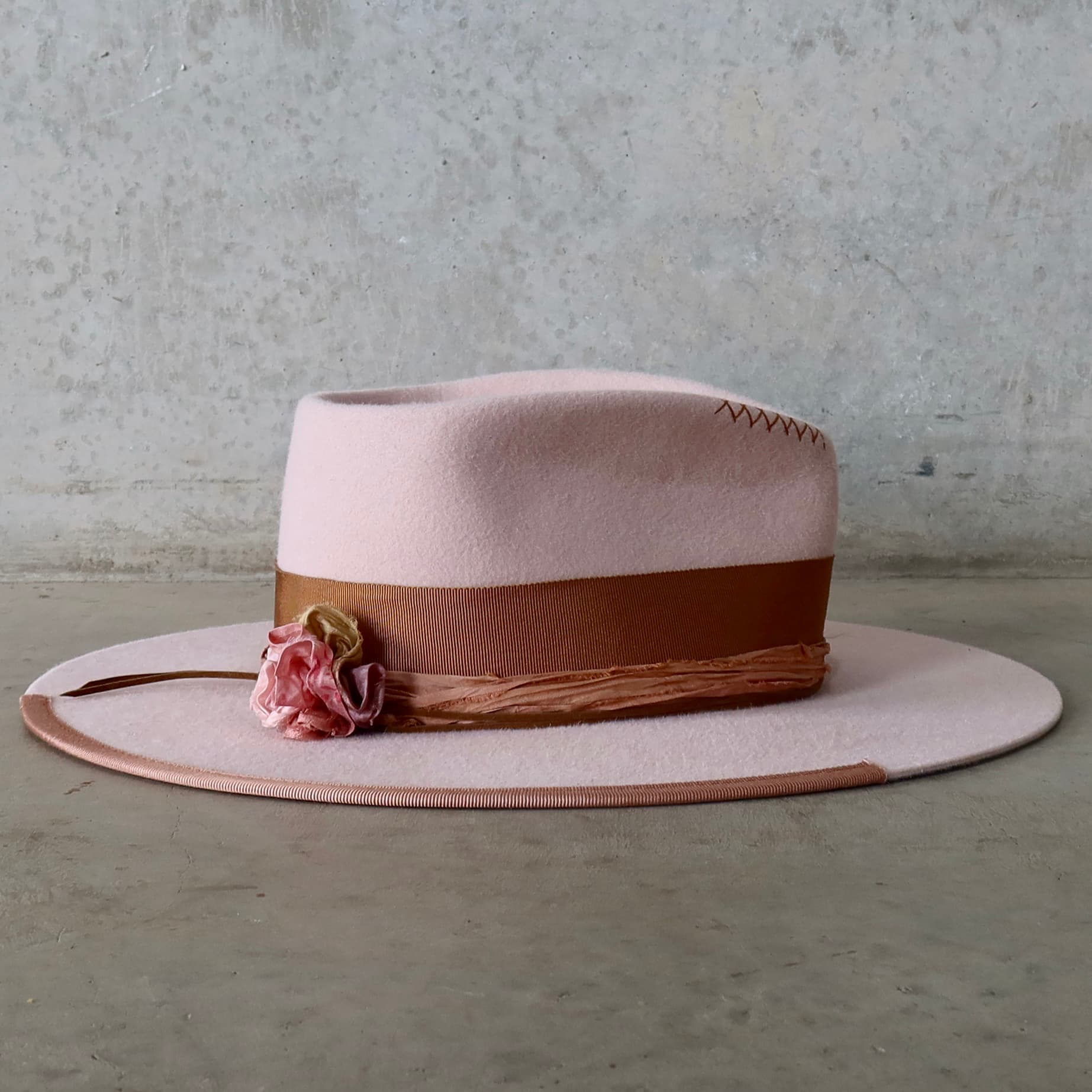 Right side view of the baby pink felt hat Lexie by PHYLLi Designs with sari silk lapel bloom and suede wraps.