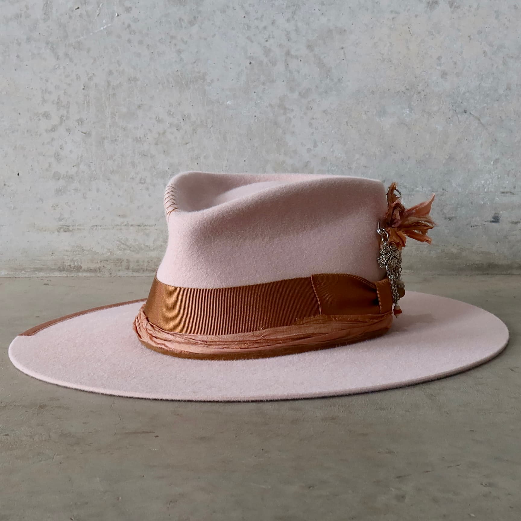 Front left angle of the baby pink felt hat Lexie by PHYLLi Designs with copper grosgrain bow band and sari silk trim.