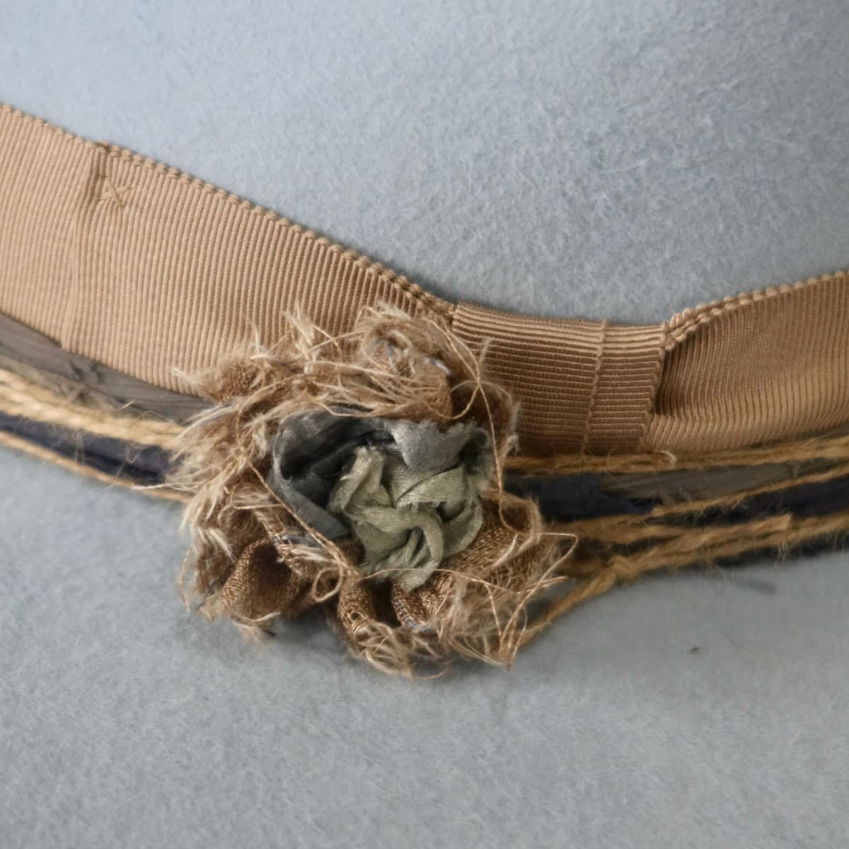 Close up detail of the Louise felt hat showing taupe Japanese grosgrain bow band and sari silk Lapel Bloom with pearl centre.