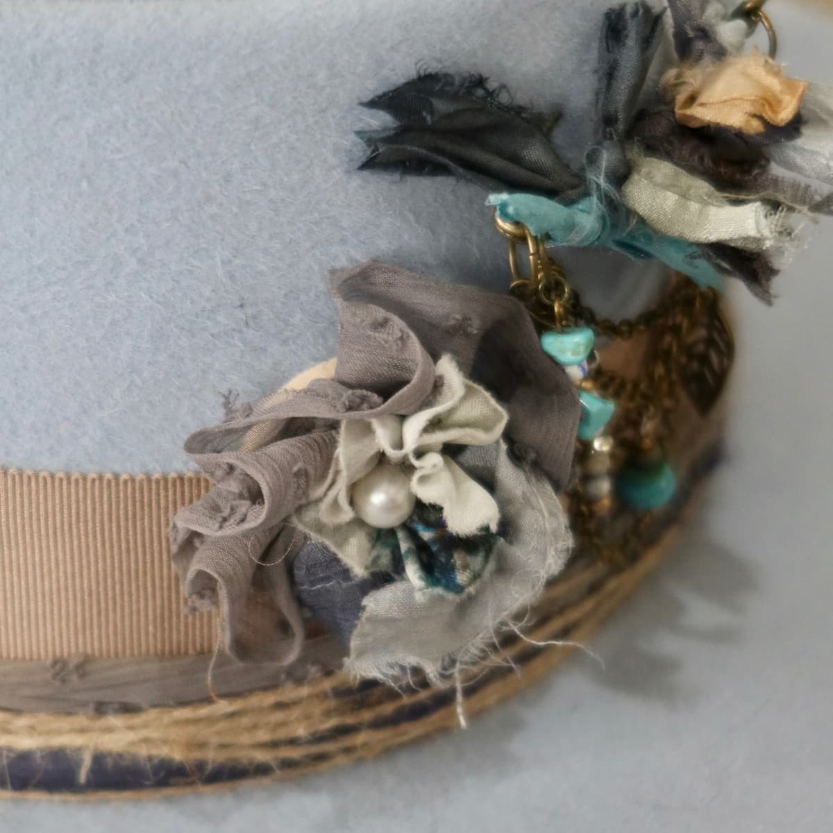 Close up detail of the Louise felt hat showing layered sari silk Lapel Bloom with pearl centre.