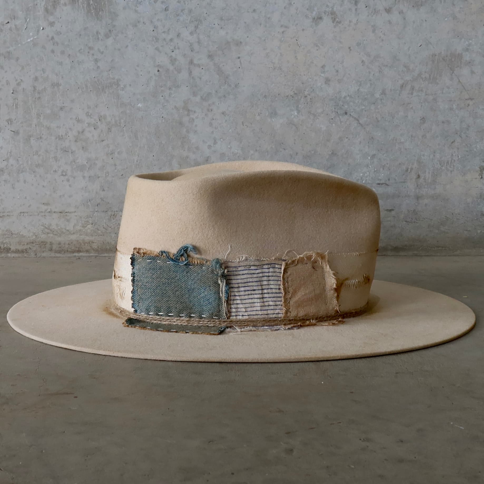 Right side view of the beige felt hat Lucille Limited Edition by PHYLLi Designs with patchwork denim, cotton, linen and silk trims.