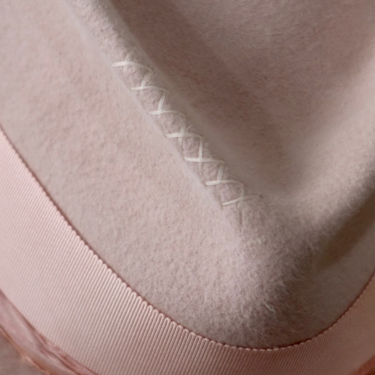 Close up detail of the Lucinda Bloom felt hat showing hand-stitched crosses in salmon.
