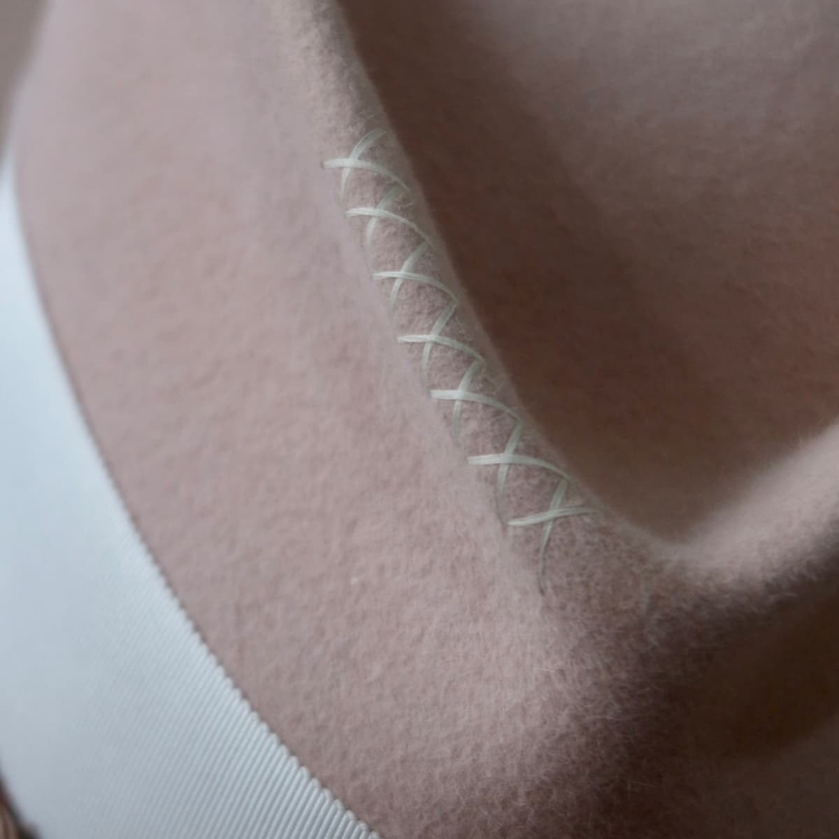 Close up detail of the Lucky Charm felt hat showing ivory hand-stitched crosses on the crown.