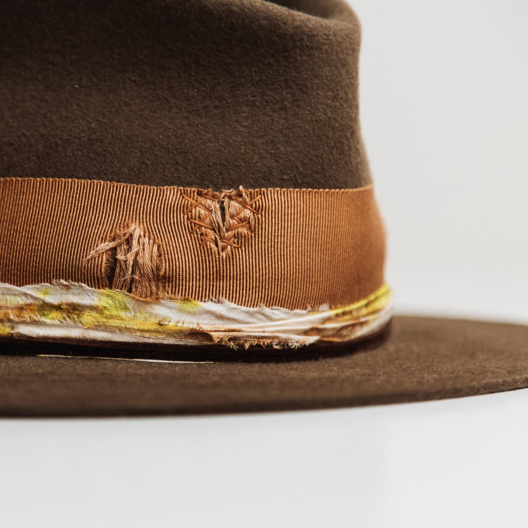 Close up detail of the Lucky Findings felt hat showing distressed copper grosgrain band with copper cross-stitch darning.