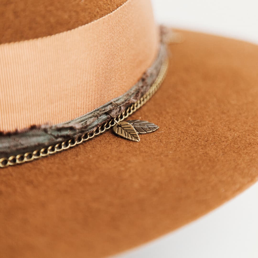 Close up detail of the Maple felt hat showing bronze crown chain with carved leaf charms and sari silk trim in Eggplant.