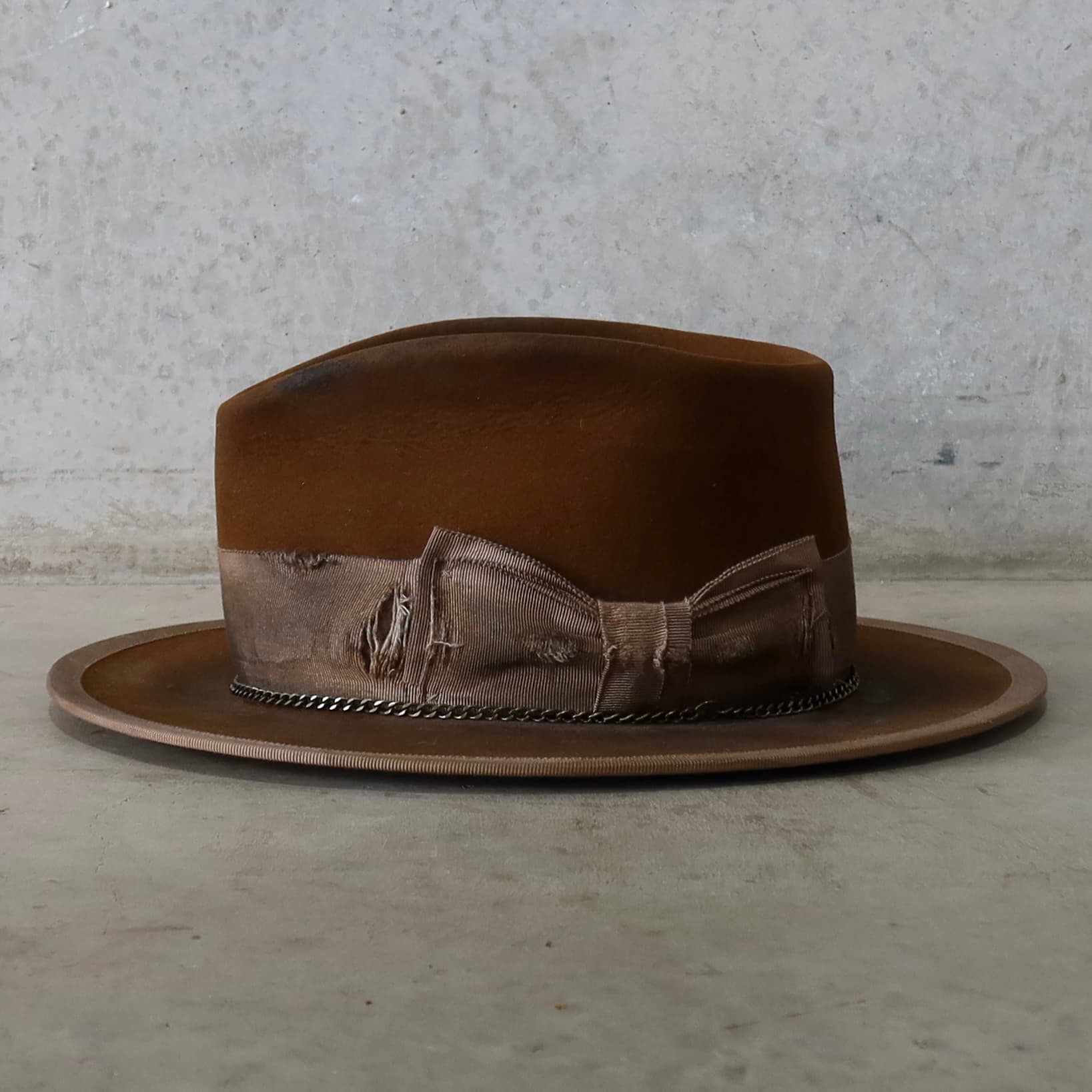 Left side view of the Marlboro Caramel distressed felt hat by PHYLLi Designs with distressed taupe grosgrain band and chocolate darned patches.
