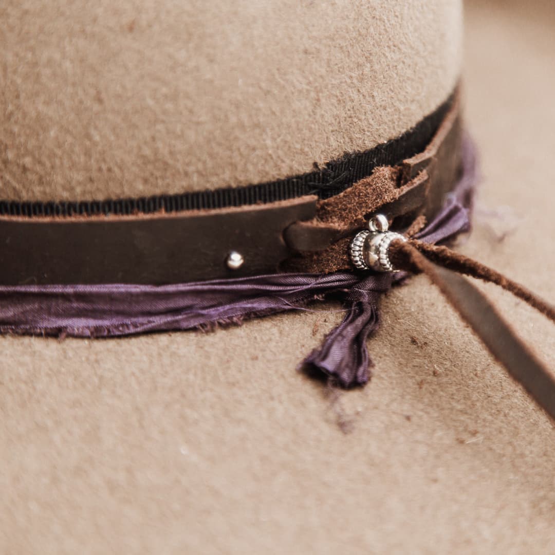 Close up detail of the Midnight Cowboy felt hat showing buffalo leather hat band tie back with midnight sari silk trim.