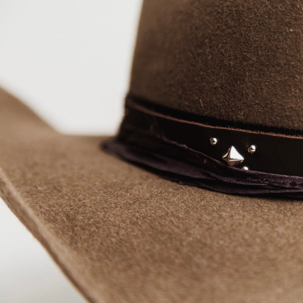 Close up detail of the Midnight Cowboy felt hat showing studded buffalo leather tieback hat band.
