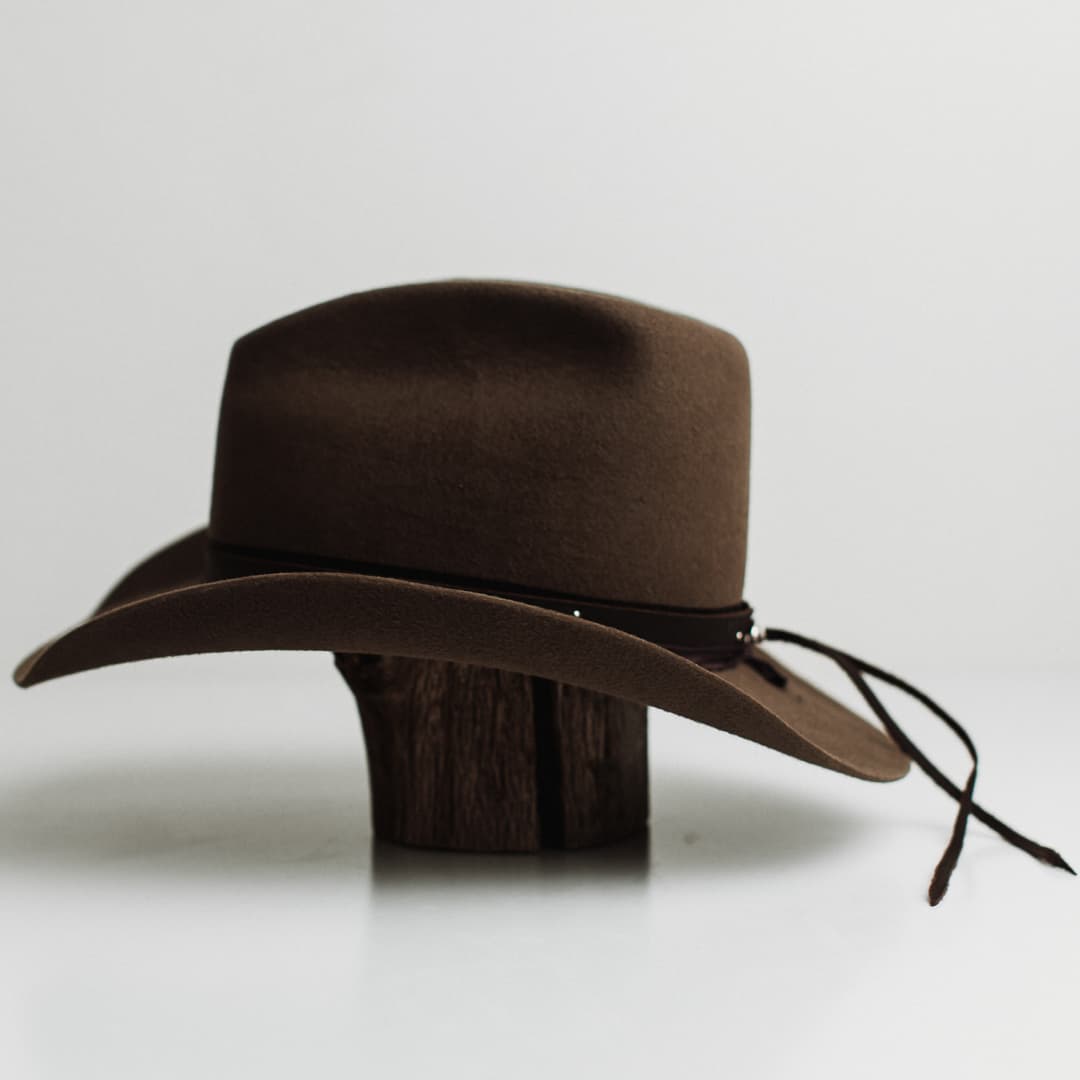 Left side view of the Midnight Cowboy dirty olive felt cowboy hat by PHYLLi Designs with studded buffalo leather tieback band and midnight sari silk trim.